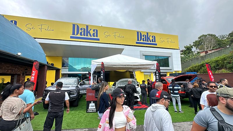 Evento de RELY frente a una tienda Daka con carpa, banderas RELY y pickups en exhibición