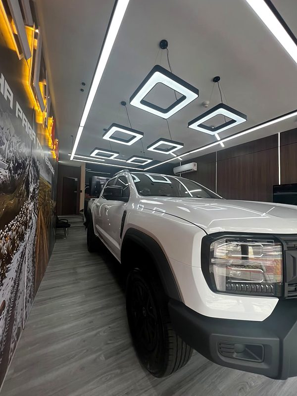 RELY R8 blanca estacionada en el showroom RELY 4x4 bajo las lámparas hexagonales